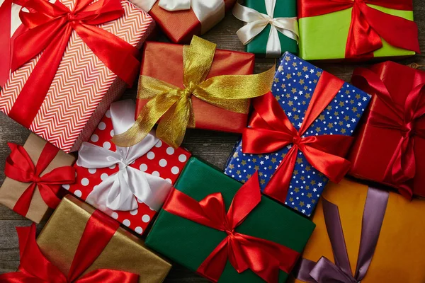 Acostado plano con regalos de Navidad envueltos en diferentes papeles de embalaje con cintas en la superficie de madera — Stock Photo