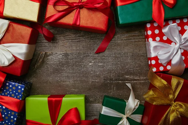 Posa piatta con regali avvolti in diverse carte da imballaggio con nastri su superficie di legno, sfondo natalizio — Foto stock