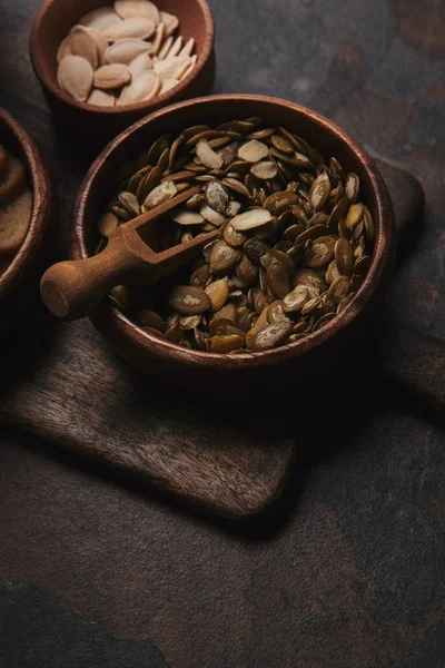 Крупный план чаши с органическими семенами тыквы на темной поверхности — стоковое фото