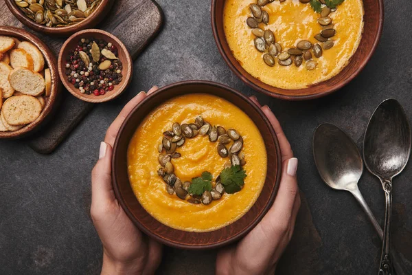 Cropped shot of person holding bowl with delicious pumpkin soup — Stock Photo