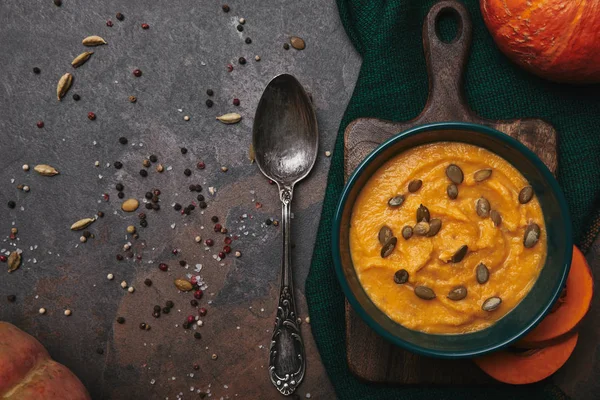 Vista dall'alto di gustosa zuppa di zucca sana in ciotola e cucchiaio su superficie scura — Foto stock