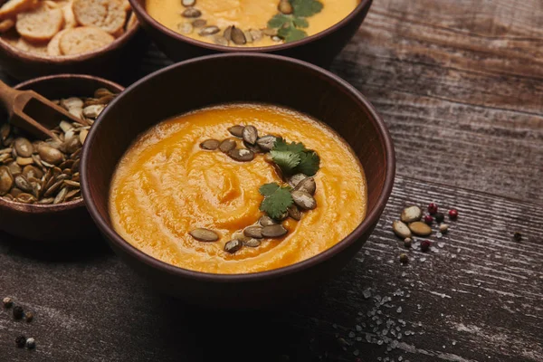 Vista de cerca de la sopa de calabaza gourmet con semillas de calabaza y especias en la mesa de madera - foto de stock