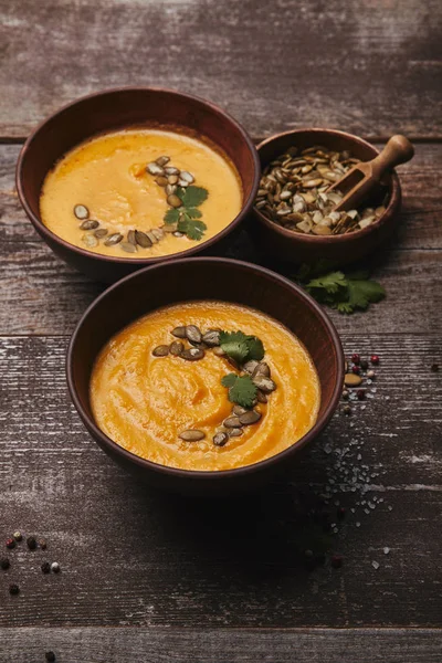 Gourmet pumpkin soup with pumpkin seeds and spices on wooden table — Stock Photo