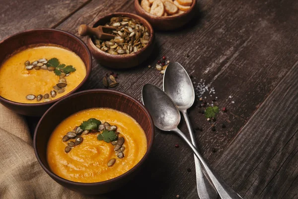 Deliziosa zuppa di zucca in ciotole e cucchiai su tavolo di legno — Foto stock