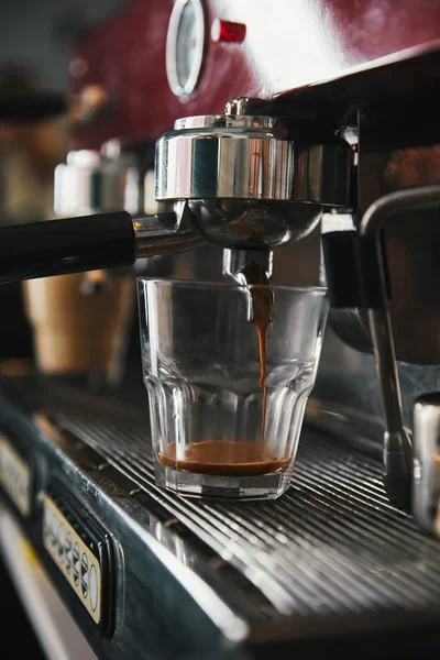 Профессиональный кофеварка и стеклянная чашка с эспрессо в кофейне — стоковое фото