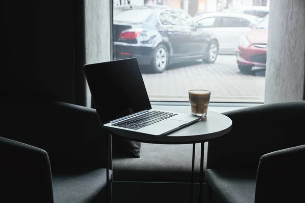Laptop with blank screen and cup of cappuccino on table in cafe — Stock Photo