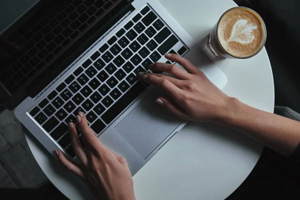 Vista dall'alto della persona che utilizza il computer portatile con schermo bianco e tazza di caffè sul tavolo — Foto stock