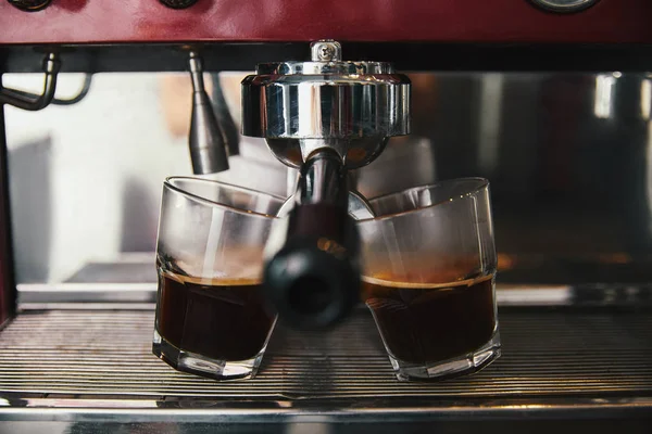 Vista de cerca de dos vasos y cafetera preparando espresso - foto de stock