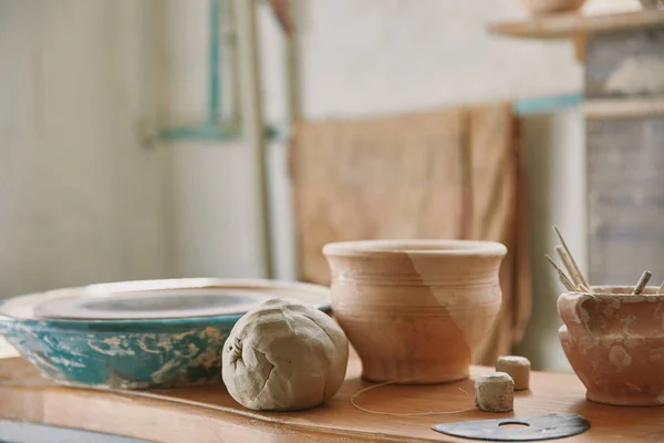 Foco seletivo de argila e ferramentas de cerâmica à mesa na oficina — Fotografia de Stock