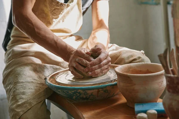 Vue partielle du potier travaillant sur la roue de poterie à l'atelier — Photo de stock