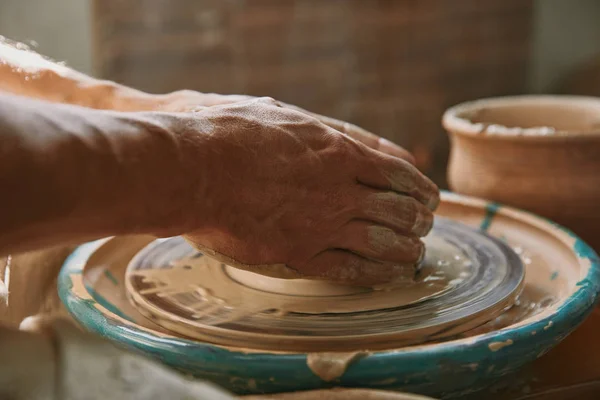 Foco seletivo de mãos de oleiro macho trabalhando na roda de cerâmica na oficina — Fotografia de Stock