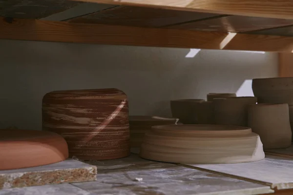 Tigelas de cerâmica e pratos em prateleiras de madeira no estúdio de cerâmica — Fotografia de Stock