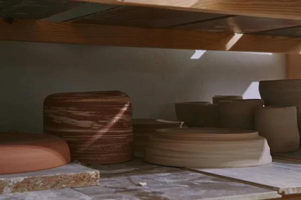 Ceramic bowls and dishes on wooden shelves at pottery studio — Stock Photo