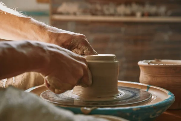 Vista ravvicinata delle mani dell'uomo che lavorano sulla ruota della ceramica in officina — Foto stock