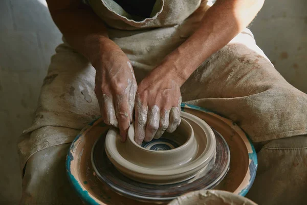 Vue partielle du potier professionnel travaillant sur la roue de poterie à l'atelier — Photo de stock