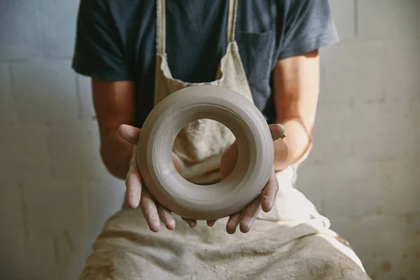 Foyer sélectif de potier professionnel dans tablier tenant l'argile au studio de poterie — Photo de stock