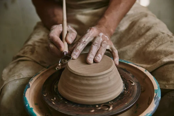 Cropped image of professional potter decorating clay pot at workshop — Stock Photo