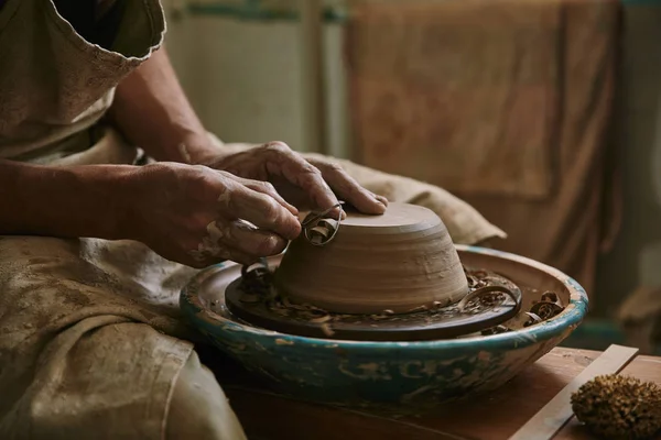 Selective focus of professional potter decorating clay pot at workshop — Stock Photo