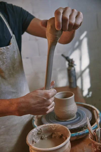 Cropped image of professional potter in apron working with clay at pottery studio — Stock Photo