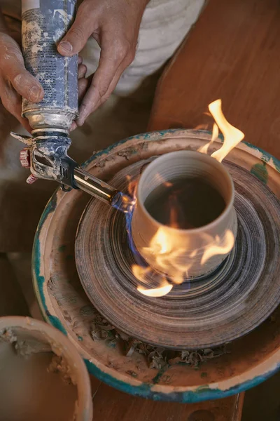 Cropped image of male potter firing clay pot at pottery studio — Stock Photo