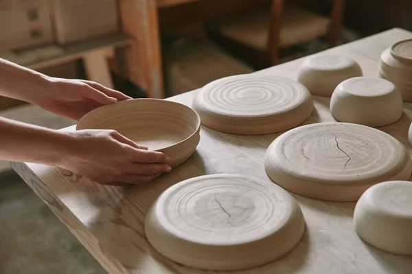 Partial view of woman putting ceramic dish on table at workshop — Stock Photo