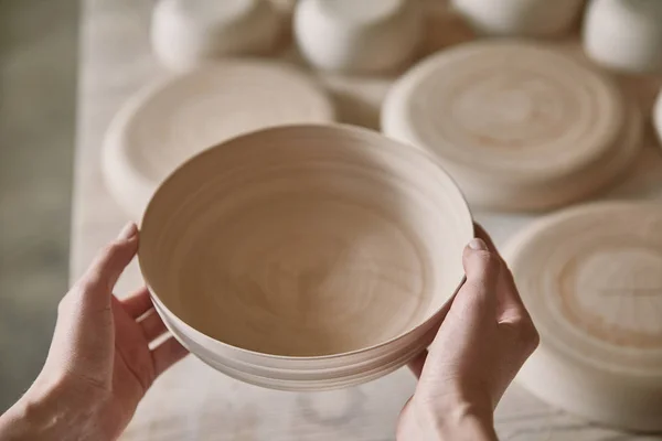 Imagem cortada de mulher segurando prato de cerâmica no estúdio de cerâmica — Fotografia de Stock