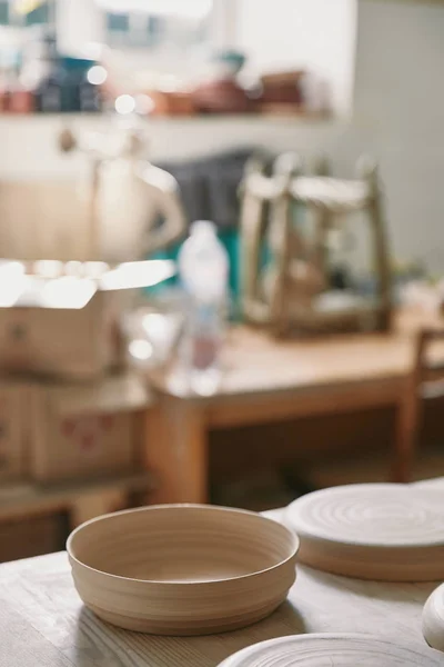 Selective focus of plates at table in pottery studio — Stock Photo