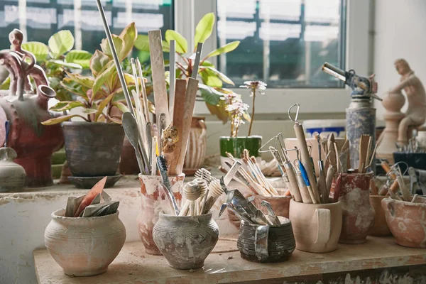 Foco seletivo de ferramentas de cerâmica e pincéis à mesa no estúdio de cerâmica — Fotografia de Stock