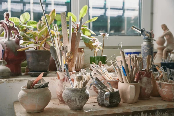 Selective focus of pottery tools and paintbrushes at table in pottery studio — Stock Photo