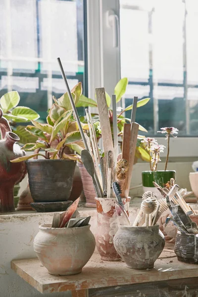 Selective focus of pottery tools and paintbrushes at table in pottery studio — Stock Photo