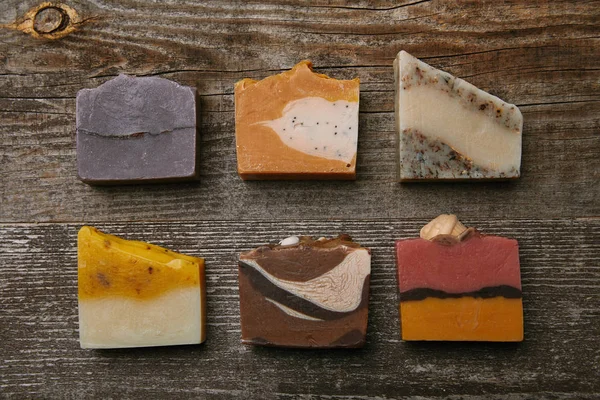Vue de dessus de différentes pièces de savon faites à la main sur plateau en bois rustique — Photo de stock