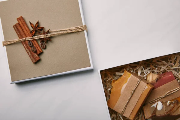 Vista dall'alto della scatola regalo decorata con sapone fatto a mano all'interno sulla superficie di marmo bianco — Foto stock