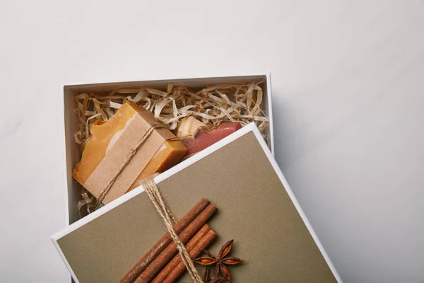 Vista dall'alto della confezione regalo con sapone fatto a mano all'interno su superficie in marmo bianco — Foto stock