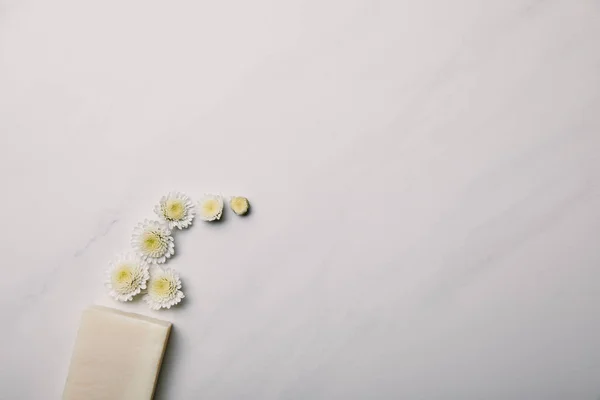 Vue de dessus du morceau de savon avec marguerites sur la surface de marbre blanc — Photo de stock