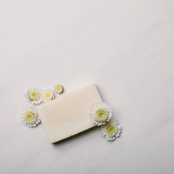 Vista superior da peça de sabão aromático branco com margaridas na superfície de mármore branco — Fotografia de Stock