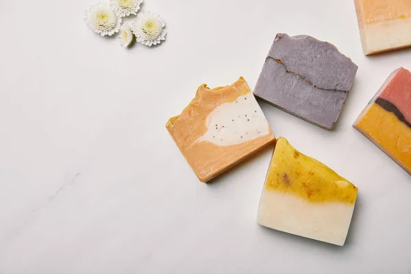 Top view of various handmade soap pieces with flowers on white marble surface — Stock Photo