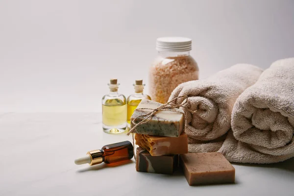 Jabón hecho a mano con diferentes suministros de masaje en la superficie de mármol blanco - foto de stock