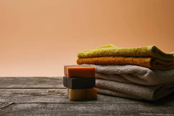 Крупным планом кусок мыла со сложенными полотенцами на деревенской деревянной столешнице — стоковое фото