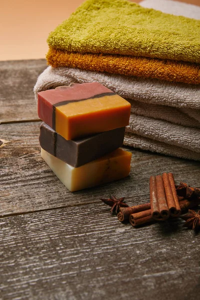 Nahaufnahme von Seifenstücken mit gestapelten Handtüchern und Gewürzen auf rustikaler Holztischplatte — Stockfoto