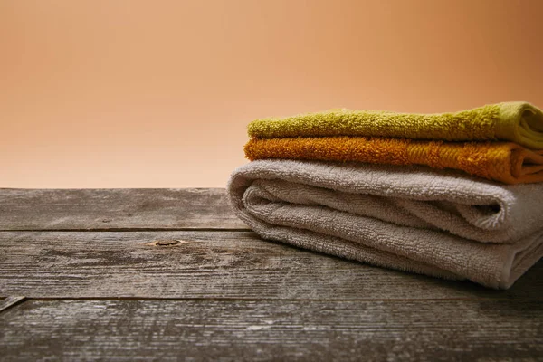 Close-up shot of stacked colorful towels on rustic wooden table — Stock Photo