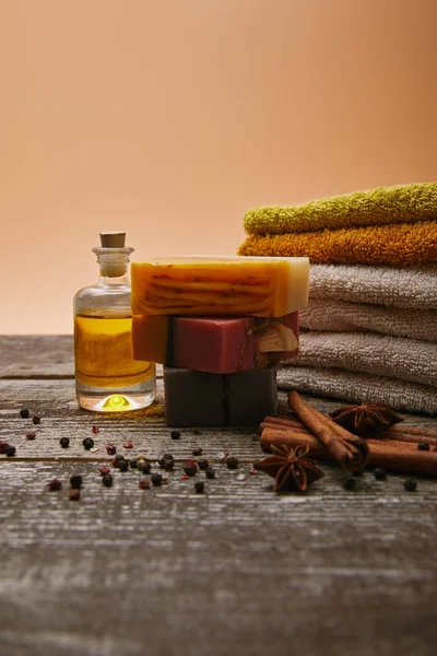 Close-up de peças de sabão com toalhas empilhadas, especiarias e óleo de massagem em mesa de madeira rústica — Fotografia de Stock