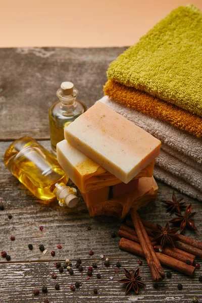 Close-up shot of aromatic soap pieces with stacked towels, spices and massage oil on rustic wooden tabletop — Stock Photo