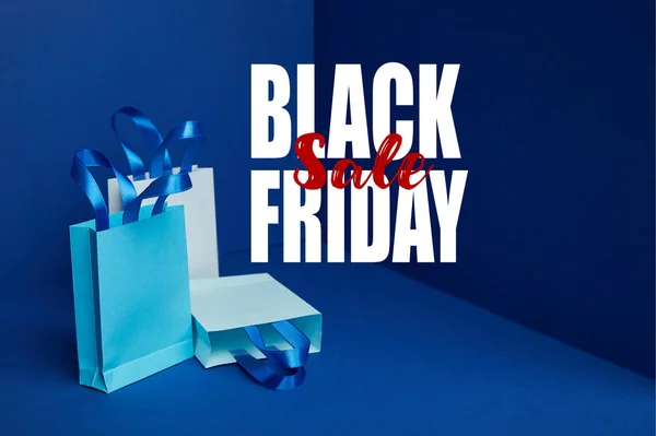 Bolsas de compras de papel arregladas en azul con venta de viernes negro - foto de stock