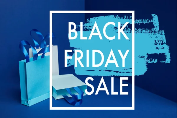 Vista ravvicinata di sacchetti di carta disposti su sfondo blu con vendita venerdì nero — Foto stock