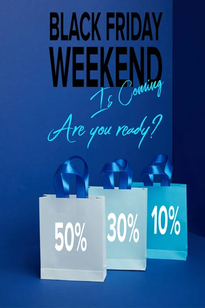 Close up view of paper shopping bags arranged on blue with black friday weekend is coming are you ready? — Stock Photo