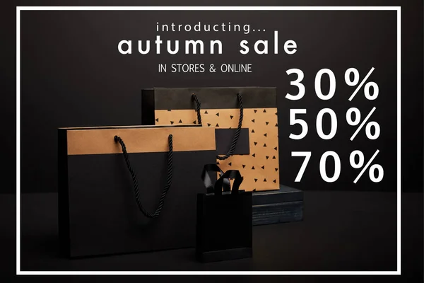 Close up vista de sacos de compras dispostos em fundo preto com venda de outono com 30, 50, 70 por cento de desconto — Fotografia de Stock