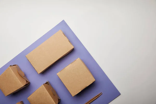 Vue surélevée des boîtes à nouilles, baguettes et boîtes à nourriture sur la surface violette — Photo de stock