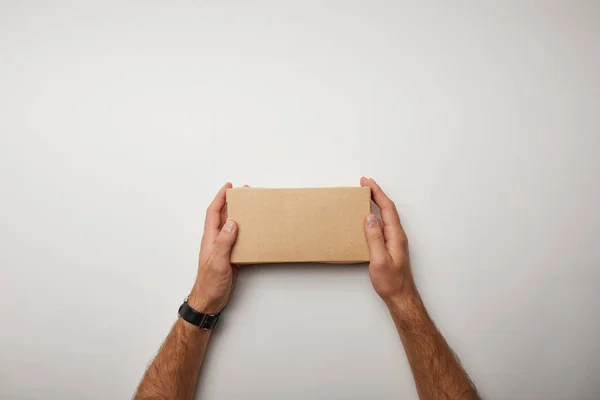 Imagen recortada del hombre sosteniendo la caja de comida de entrega en la superficie blanca - foto de stock