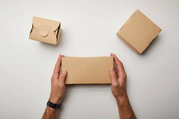 Visão parcial do homem sentado à mesa com caixas de comida de papelão — Fotografia de Stock