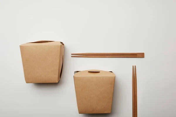 Flat lay with arranged wok boxes and chopsticks on white surface, minimalistic concept — Stock Photo